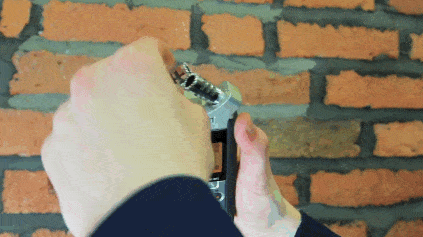 This is a gif of the Zoom h4n being used, a square mic, and it is being adjusted against a brick wall backdrop. The screen is orange and changes with the click of a button.g Microphone